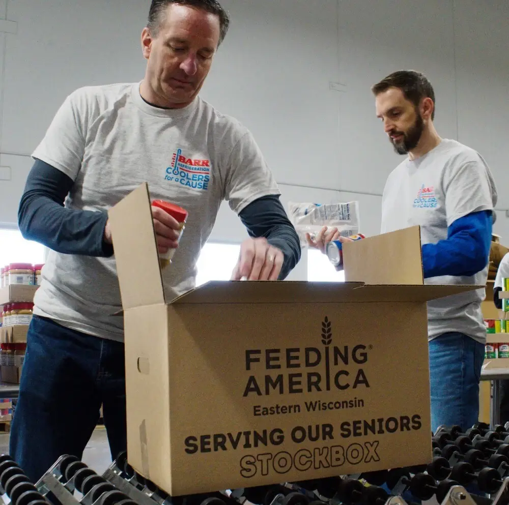 Barr Refrigeration CEO Christopher Piotrowski and Senior Marketing Manager Erik Kielisch packing food boxes for senior citizens at Feeding America Eastern Wisconsin